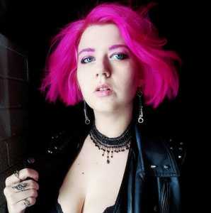 Alese with pink hear wearing a black leather jacket and a handmade necklace